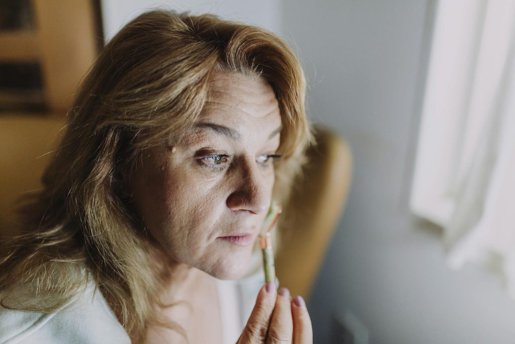 A woman applying a skincare product indoors, focusing on relaxation and self-care.