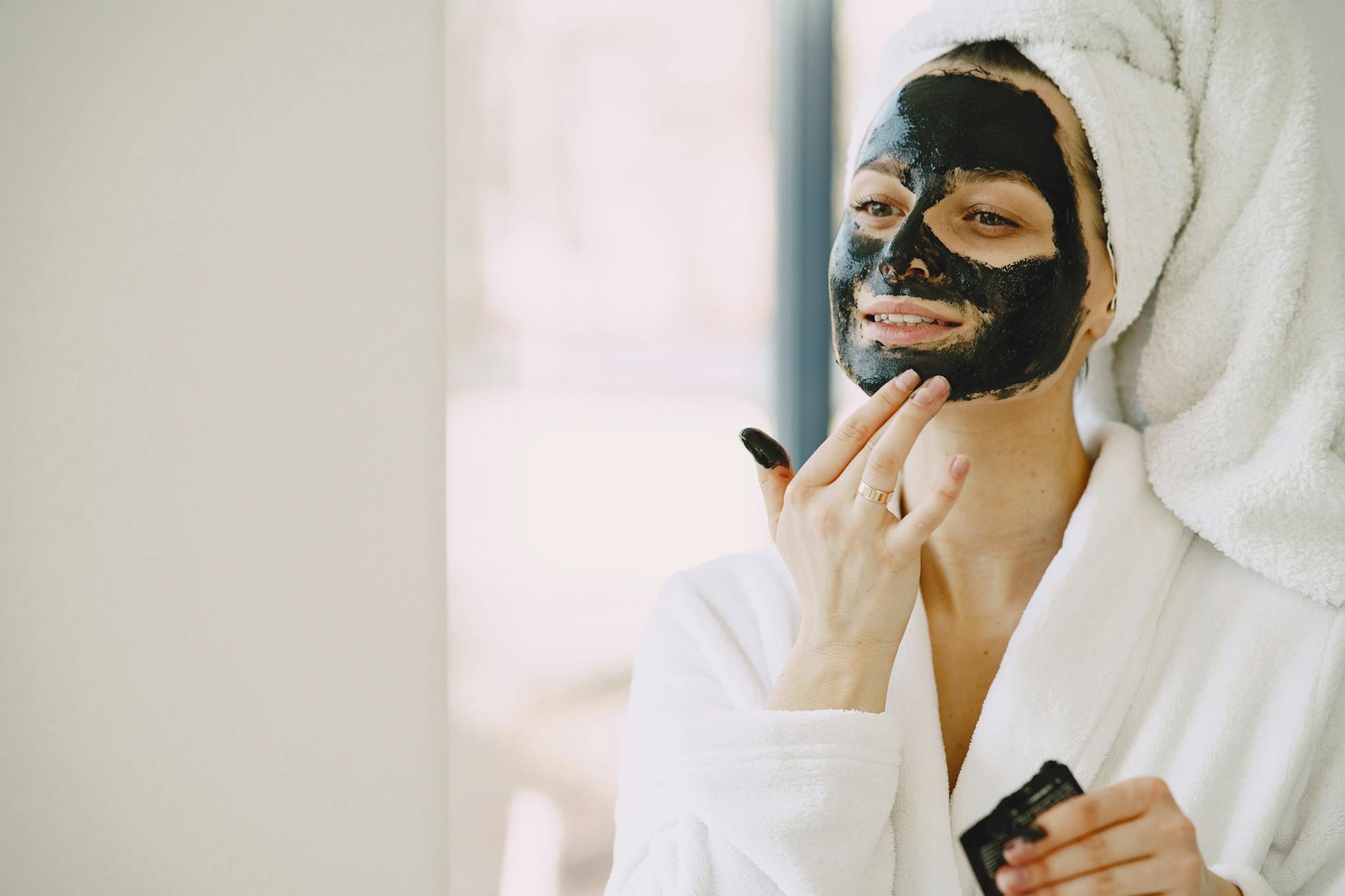 Adult woman enjoying a relaxing skincare routine, applying a facial mask indoors.